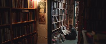 Movie still from “Berlin Syndrome” (2017), directed by Cate Shortland – A woman sitting on the floor in front of a book shelf; Wide shot, High angle