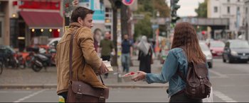 Movie still from “Berlin Syndrome” (2017), directed by Cate Shortland – A man handing a box to a woman on the street; Medium shot, Over the shoulder angle