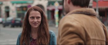 A woman is standing in front of a man on the street