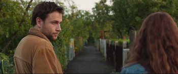 Movie still from “Berlin Syndrome” (2017), directed by Cate Shortland – A man standing on a sidewalk near trees; Close Up shot, Over the shoulder angle