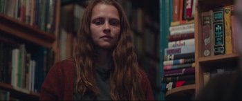 Movie still from “Berlin Syndrome” (2017), directed by Cate Shortland – A woman with long brown hair standing in front of a book shelf; Close Up shot, Low angle