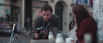 Movie still from “Berlin Syndrome” (2017), directed by Cate Shortland – A man sitting at a table looking at a camera; Close Up shot, Over the shoulder angle
