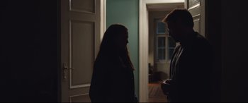 Movie still from “Berlin Syndrome” (2017), directed by Cate Shortland – Two people are standing in a room in the dark; Medium shot, Over the shoulder angle