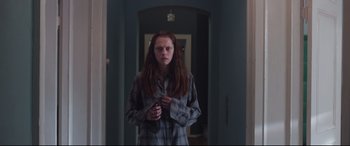 Movie still from “Berlin Syndrome” (2017), directed by Cate Shortland – A woman standing in a hallway holding a cell phone; Medium shot, Low angle