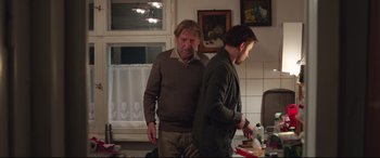 Movie still from “Berlin Syndrome” (2017), directed by Cate Shortland – Two men standing in a kitchen next to a window; Medium shot, Over the shoulder angle