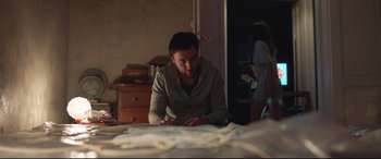 Movie still from “Berlin Syndrome” (2017), directed by Cate Shortland – A man sitting at a table in a room; Medium shot, Over the shoulder angle