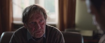 Movie still from “Berlin Syndrome” (2017), directed by Cate Shortland – An old man with a beard and a sweater on; Close Up shot, Over the shoulder angle