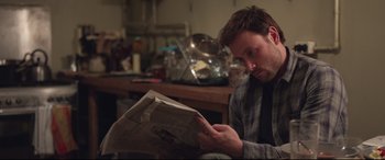 Movie still from “Berlin Syndrome” (2017), directed by Cate Shortland – A man sitting down reading a newspaper in a kitchen; Medium shot, Over the shoulder angle