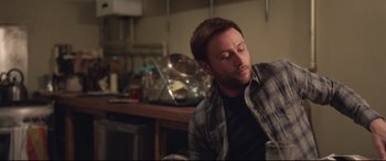 Movie still from “Berlin Syndrome” (2017), directed by Cate Shortland – A man sitting in front of a table in a kitchen; Medium shot, Over the shoulder angle