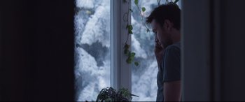 Movie still from “Berlin Syndrome” (2017), directed by Cate Shortland – A man sitting in front of a window looking outside; Medium shot, Over the shoulder angle