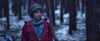Movie still from “Berlin Syndrome” (2017), directed by Cate Shortland – A boy in a red jacket and a green hat in the woods; Medium shot, Low angle
