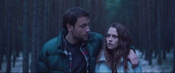 Movie still from “Berlin Syndrome” (2017), directed by Cate Shortland – A man and a woman standing next to each other in the woods; Medium shot, Low angle