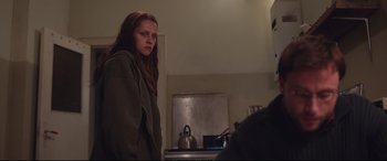 Movie still from “Berlin Syndrome” (2017), directed by Cate Shortland – A woman standing in front of a stove in a kitchen; Medium shot, Over the shoulder angle
