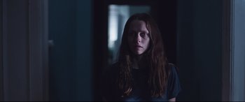 Movie still from “Berlin Syndrome” (2017), directed by Cate Shortland – A woman with long brown hair standing in a dark room; Medium shot, Low angle