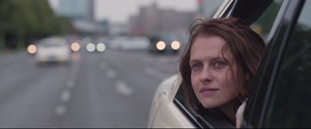 Movie still from “Berlin Syndrome” (2017), directed by Cate Shortland – A woman sitting in the drivers seat of a white car; Close Up shot, Low angle