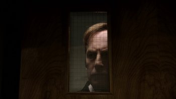 Movie still from “Better Call Saul” (2015), created by Vince Gilligan – A man in a suit looking through a window; Close Up shot, Low angle