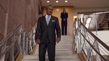 Movie still from “Better Call Saul” (2015), created by Vince Gilligan – A man in a suit and tie standing in front of a woman in a suit; Wide shot, Low angle