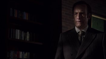 Movie still from “Better Call Saul” (2015), created by Vince Gilligan – A man wearing a suit and tie in a dark room; Close Up shot, Low angle