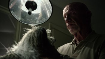 An old man holding a white dog in a room