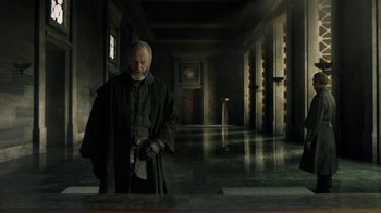 Movie still from “Game of Thrones” (2011), created by D.B. Weiss – An old man standing in a dark room holding a knife; Wide shot, Low angle