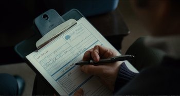 Movie still from “Win Win” (2011), directed by Tom McCarthy – A person is writing on a paper with a pen on top of it; Close Up shot, Over the shoulder angle