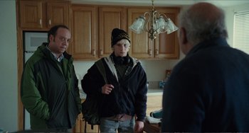 Movie still from “Win Win” (2011), directed by Tom McCarthy – Two men and a woman standing in a kitchen; Medium shot, Over the shoulder angle