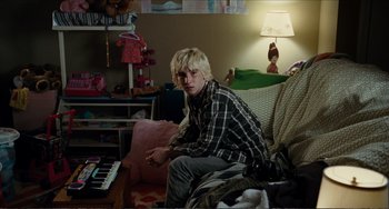 Movie still from “Win Win” (2011), directed by Tom McCarthy – A man sitting on top of a couch in a living room; Medium shot, Over the shoulder angle