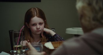Movie still from “Win Win” (2011), directed by Tom McCarthy – A young girl sitting at a table with a glass of water; Close Up shot, Over the shoulder angle