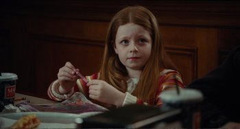 Movie still from “Win Win” (2011), directed by Tom McCarthy – A young girl sitting at a table and holding a pair of scissors; Medium shot, High angle
