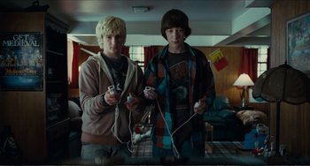 Movie still from “Win Win” (2011), directed by Tom McCarthy – Two young men holding wii remotes in a living room; Medium shot, High angle