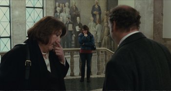 Movie still from “Win Win” (2011), directed by Tom McCarthy – A woman standing next to two men in front of a painting; Wide shot, Over the shoulder angle