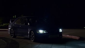 A car is parked on the side of the road at night