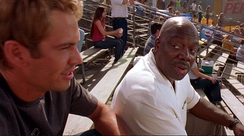 Movie still from “2 Fast 2 Furious” (2003), directed by John Singleton – Two men sitting on bleachers talking to each other; Close Up shot, Over the shoulder angle