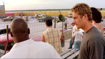Movie still from “2 Fast 2 Furious” (2003), directed by John Singleton – A group of men standing around a fence; Close Up shot, Over the shoulder angle