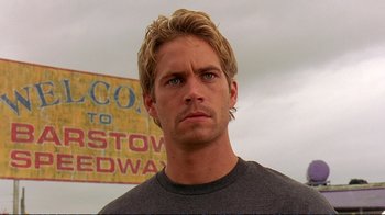 Movie still from “2 Fast 2 Furious” (2003), directed by John Singleton – A person with a sign in the background; Close Up shot, Over the shoulder angle