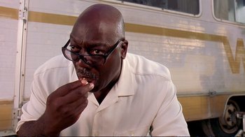 Movie still from “2 Fast 2 Furious” (2003), directed by John Singleton – A man in a white dress shirt and glasses is taking a bite out of a piece of food; Close Up shot, Low angle