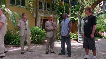Movie still from “2 Fast 2 Furious” (2003), directed by John Singleton – A group of men standing next to each other on a brick walkway; Wide shot, Low angle