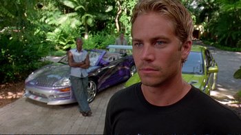 Movie still from “2 Fast 2 Furious” (2003), directed by John Singleton – A man standing in front of a purple car and another man standing in front of a purple car; Close Up shot, Over the shoulder angle