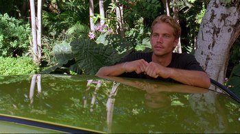 Movie still from “2 Fast 2 Furious” (2003), directed by John Singleton – A man leaning up against a car in the woods; Medium shot, Over the shoulder angle