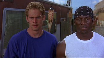 Movie still from “2 Fast 2 Furious” (2003), directed by John Singleton – Two men standing next to each other in front of a building; Close Up shot, Low angle