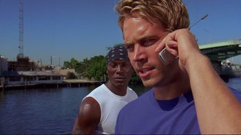 Movie still from “2 Fast 2 Furious” (2003), directed by John Singleton – Two men standing next to a body of water talking on a cell phone; Close Up shot, Over the shoulder angle
