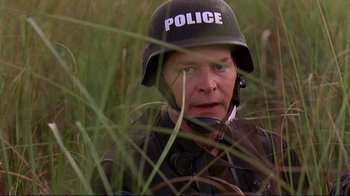 Movie still from “2 Fast 2 Furious” (2003), directed by John Singleton – A man in a police helmet is sitting in the grass; Close Up shot, Over the shoulder angle