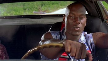 Movie still from “2 Fast 2 Furious” (2003), directed by John Singleton – A man driving in a car with a steering wheel; Close Up shot, Low angle