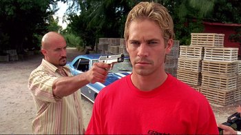 Movie still from “2 Fast 2 Furious” (2003), directed by John Singleton – A man pointing a gun at a man in a red t - shirt; Close Up shot, Over the shoulder angle