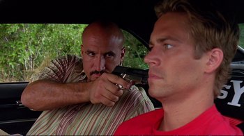 Movie still from “2 Fast 2 Furious” (2003), directed by John Singleton – A man holding a gun pointed at another man in the back of a car; Close Up shot, Over the shoulder angle