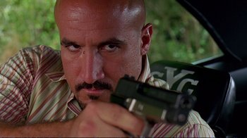 Movie still from “2 Fast 2 Furious” (2003), directed by John Singleton – A bald man holding a gun while standing next to a tree; Close Up shot, Low angle