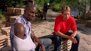 Movie still from “2 Fast 2 Furious” (2003), directed by John Singleton – A group of people sitting on top of a wooden bench; Medium shot, Low angle