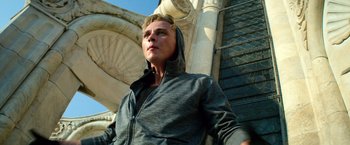 Movie still from “6 Underground” (2019), directed by Michael Bay – A young man wearing a gray hoodie standing in front of a building; Medium shot, Low angle