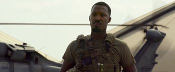 Movie still from “6 Underground” (2019), directed by Michael Bay – A man in a military uniform with a gun strapped to his chest; Close Up shot, Over the shoulder angle