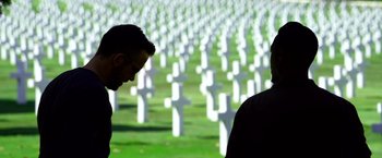Movie still from “6 Underground” (2019), directed by Michael Bay – Two men standing in front of a field of white crosses; Close Up shot, Over the shoulder angle